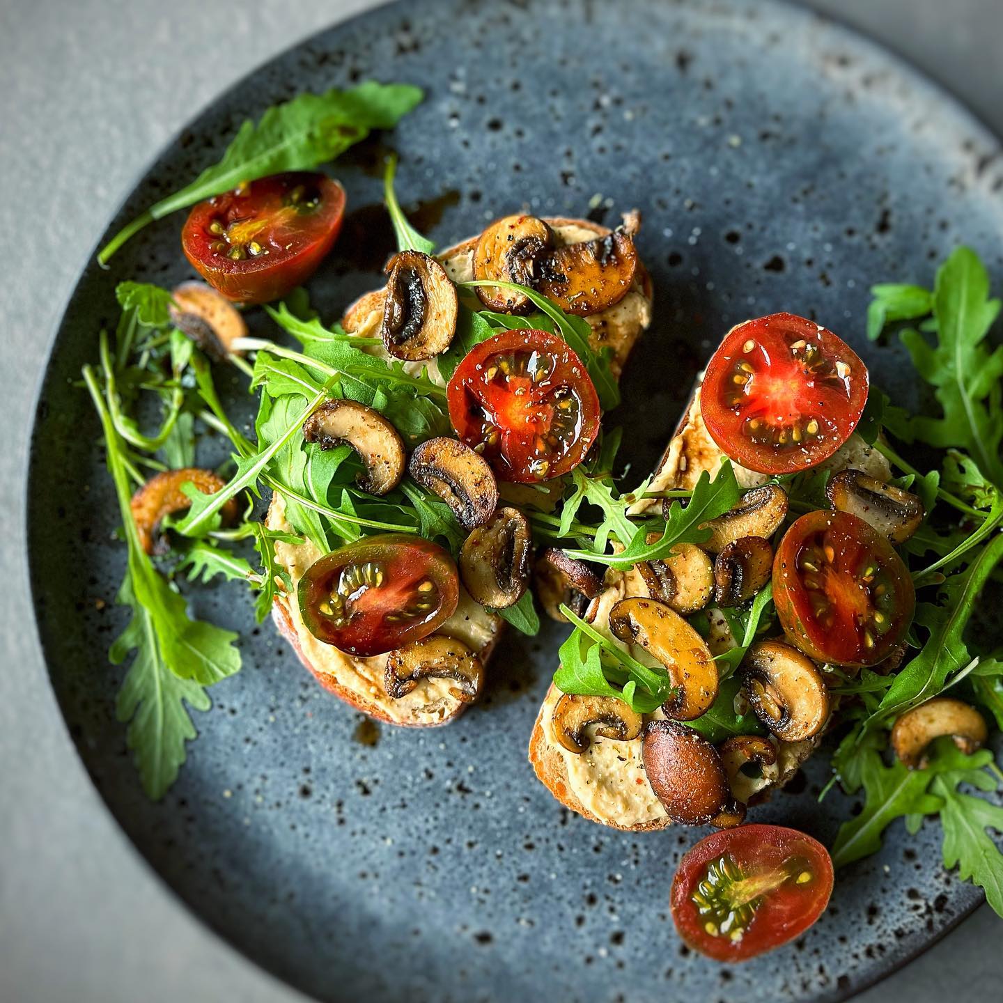 Toasted sourdough with creamy hummus, tomatoes, mushrooms, arugula, and balsamic
