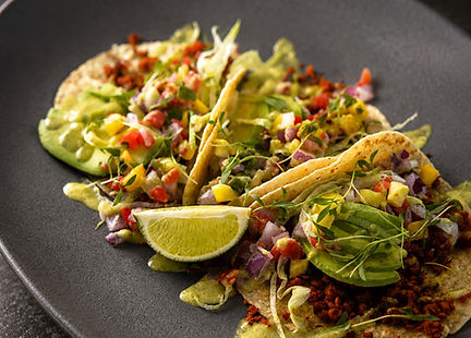 Vegan soyrizo tacos with pineapple pico de gallo, red cabbage, cilantro, avocado jalapeño crema, and lime