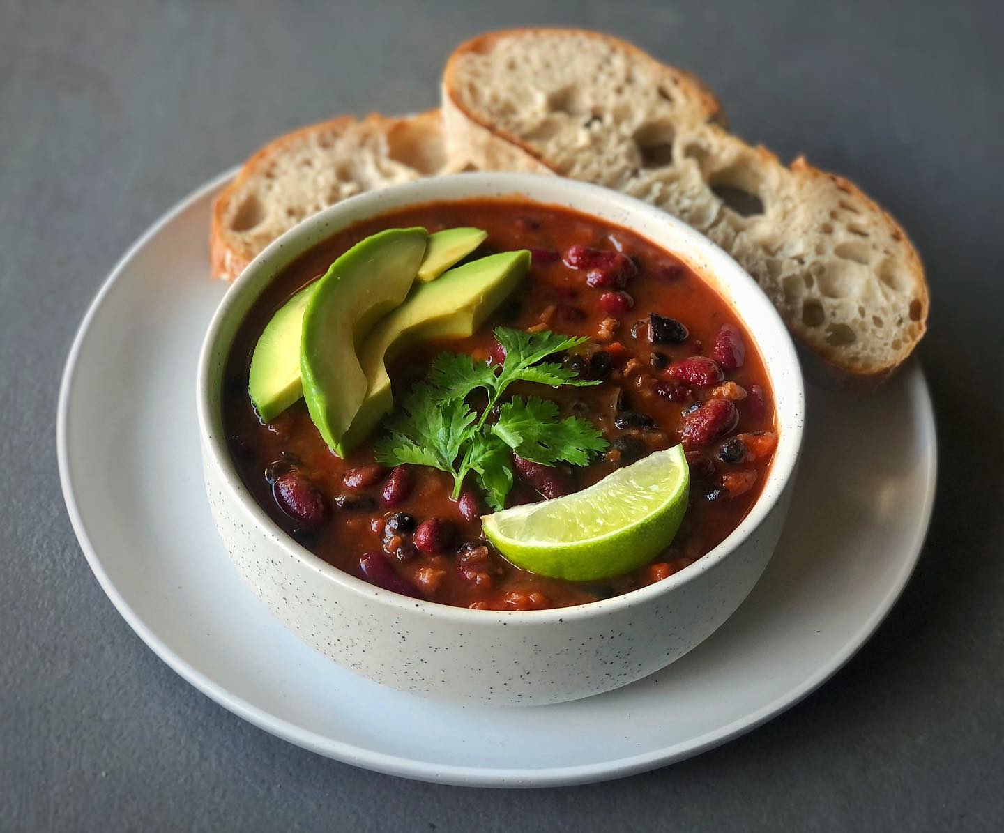 Spicy vegan chili sin carne with black beans, kidney beans, tomatoes, chipotle, and avocado
