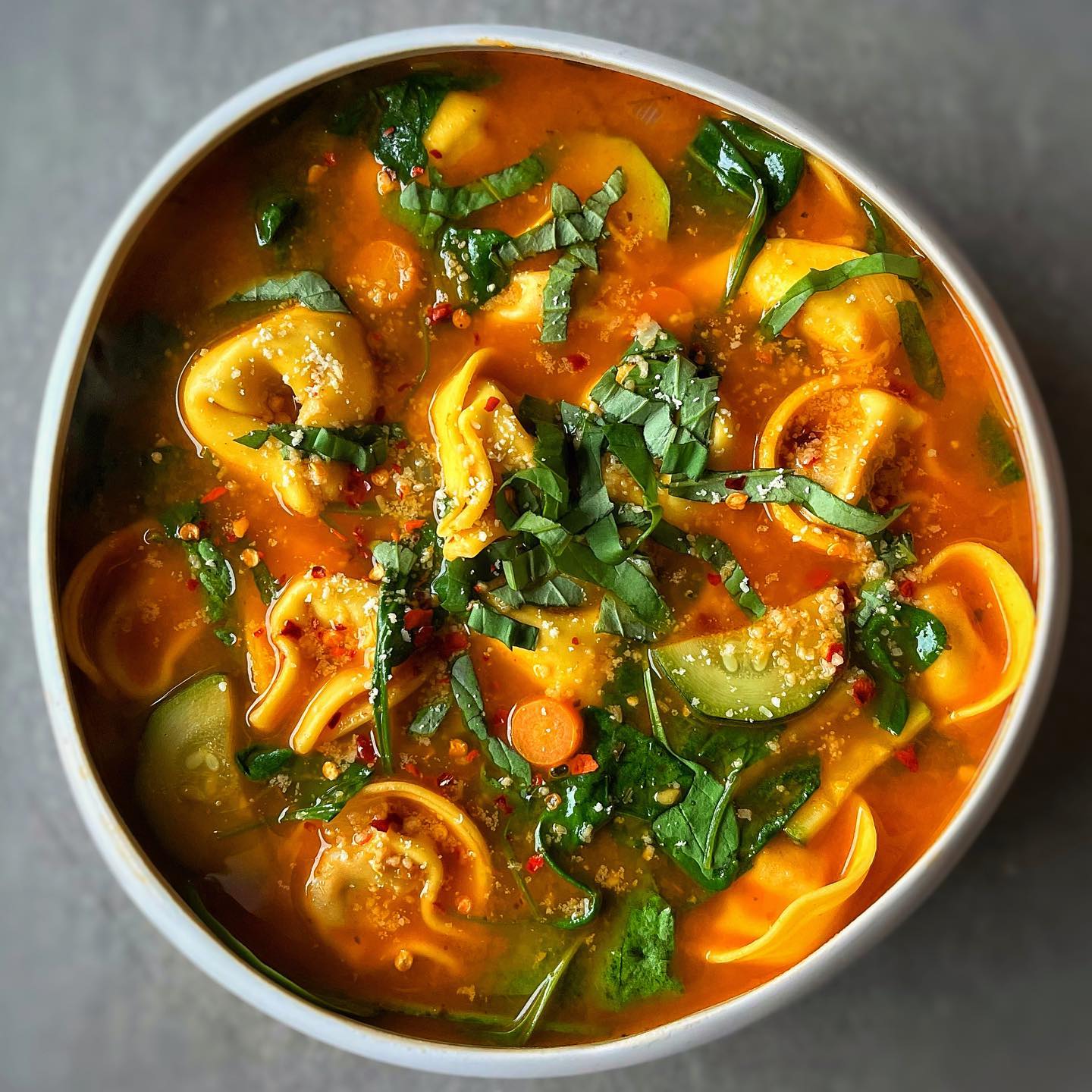 Vegan tortellini tomato basil soup with vegetables, spinach, and fresh basil