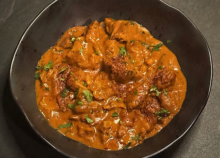 Creamy tofu butter chicken curry with cilantro, chili flakes, rice, and naan