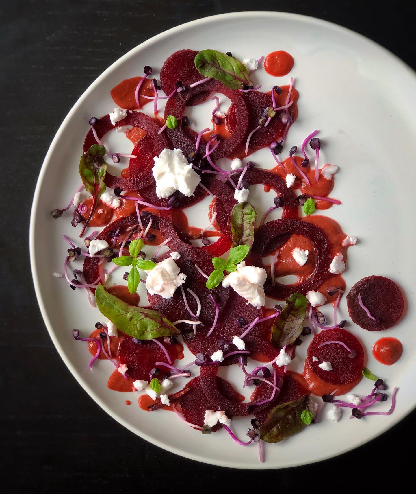 Vegan beetroot carpaccio with creamy beet dressing, greens, basil, microgreens, and feta