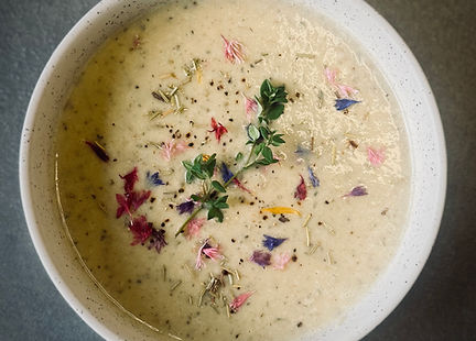 Creamy roasted cauliflower soup topped with thyme and cracked black pepper