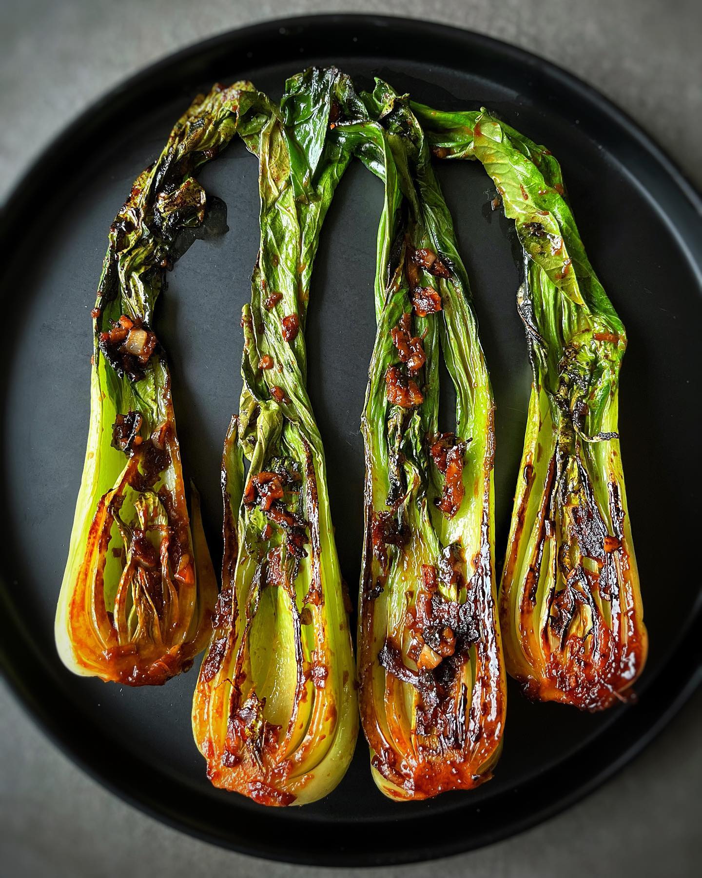 Charred miso glazed baby bok choy with caramelized garlic, ginger, soy sauce, and sriracha