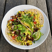 Vegan breakfast tacos with tofu scramble, avocado, salsa, cilantro, jalapeños, hot sauce, and lime