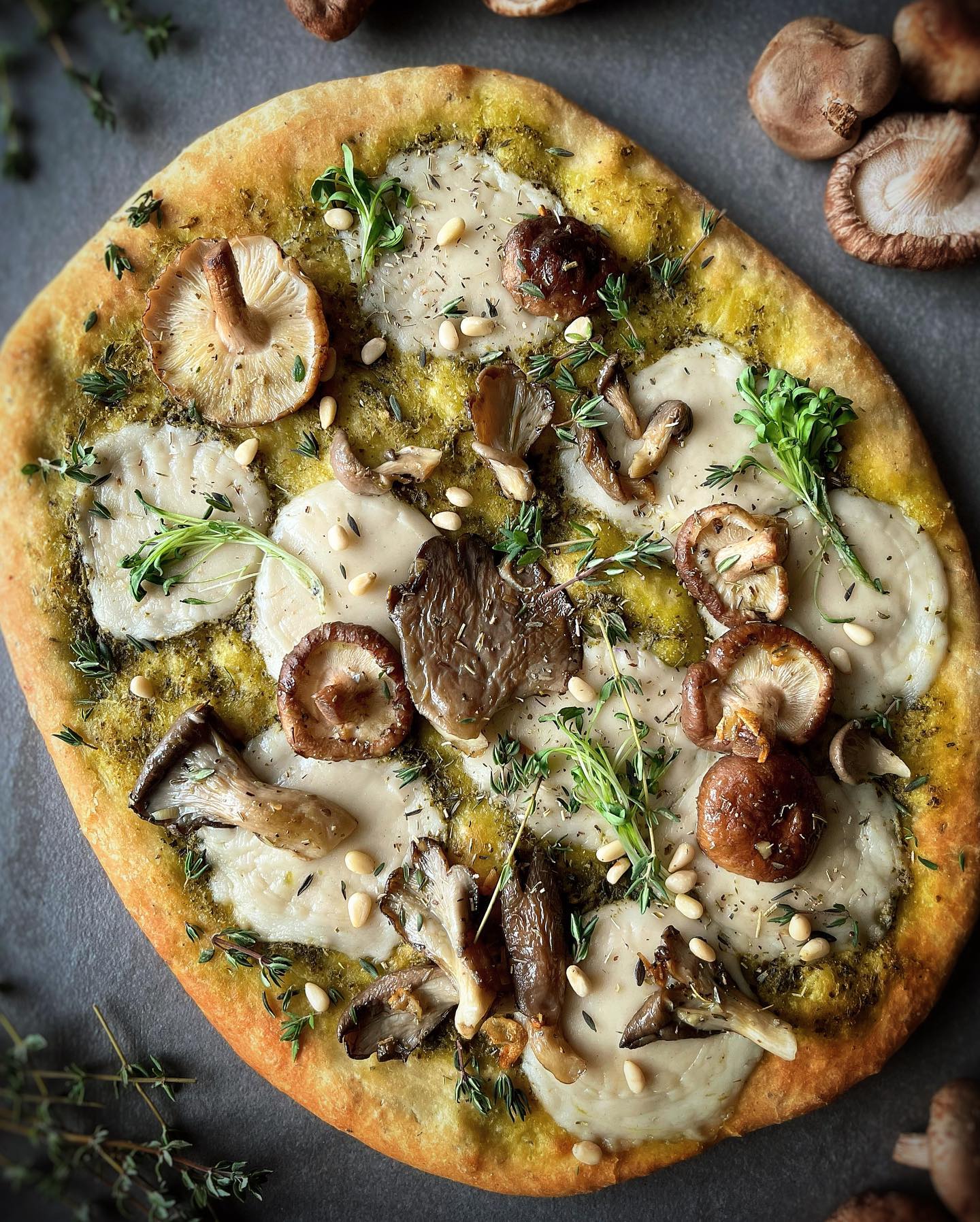 Wild mushroom pizza with garlic herb crust, basil pesto, vegan mozzarella, and microgreens