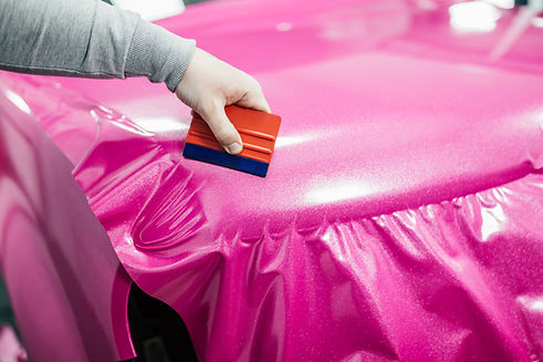 Car wrapping specialist putting vinyl foil or film on car Selective focus .jpg
