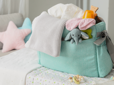 A turquoise birth bag sits on a grey blanket. It's bursting with things you may bring to your birth while being supported by a doula in Ottawa.
