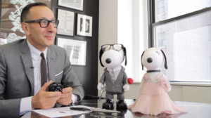 a man in a suite next to two dog figures, one in a shirt and jacket and one in a pink dress