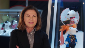 a woman in a shirt and jacket in front of figures of dogs in a tophat and kimono