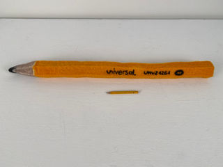 Image of a felted golf pencil scaled up to about 24 inches long next to a standard golf pencil on a white background.