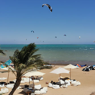 Der Makani Beach Club in El Gouna. Blick auf die Sonnenliegen und aufs Meer. Es sind viele Kitesurfer auf dem Wasser.