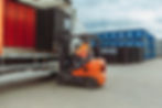photo of man on fork lift truck unloading black plastic sowing trays from side of a lorry