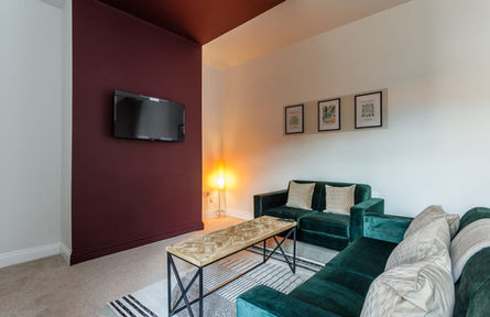 Modern living room with green sofas and burgundy wall