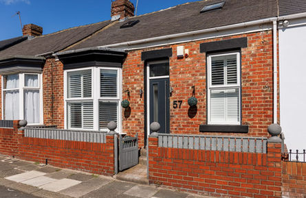 Red brick terraced house with black door number 57