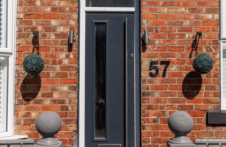 Dark gray front door on a red brick house, number 57