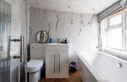 Bathroom with marble walls, shower, toilet, vanity, and tub