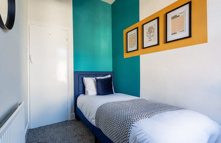 Small bedroom with single bed, teal and yellow accent walls.