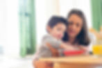 A young boy with food aversion is exploring a bowl of food while an adult looks on and helps him.