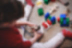 A young boy plays with some little mice toys and some building blocks during a play therapy session.