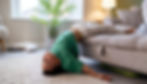 A young black boy hangs upside down off a sofa. His hands and face are relaxed.