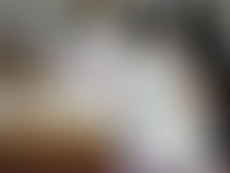 A person reviews and sorts official election ballots at a table, with other workers and ballot envelopes visible in the background.