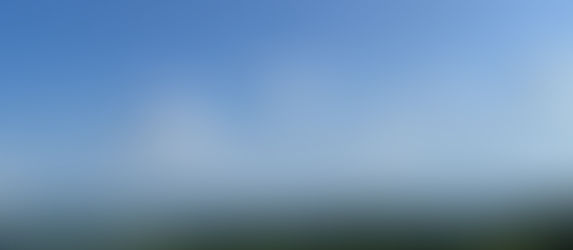 Un ciel bleu avec plein de petits nuages et une étendue verte, au loin une rivière