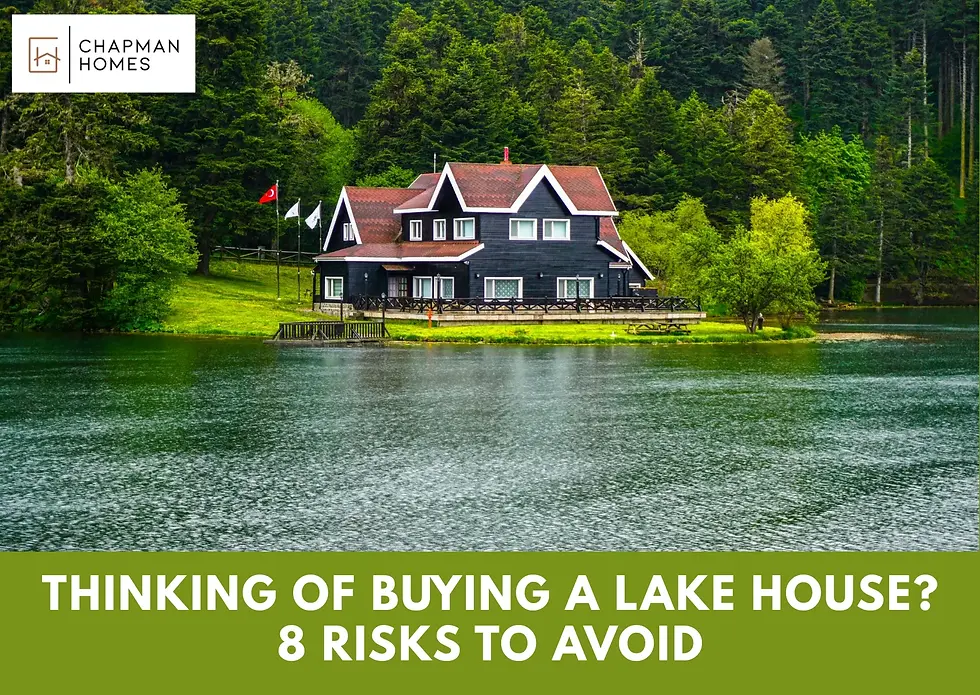 Chapman Homes blog featured image showing a large dark lakefront home surrounded by evergreen trees reflected in calm lake water, titled "Will You Regret Buying a Lake House? 8 Risks to Avoid"