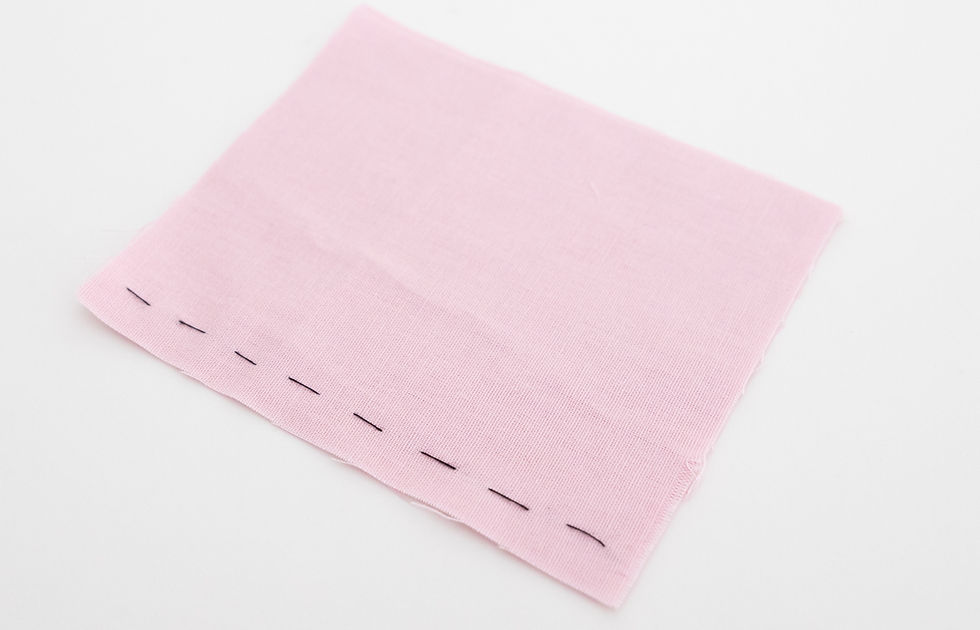 Some pink fabric with black basting stitches.