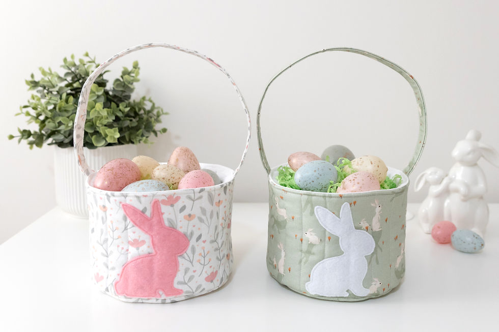 Whie and green Easter baskets with bunny appliques on the front sitting on a table.