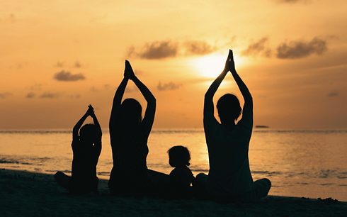 Een mediterende familie op een rij op het strand met de zonsondergang eronder.png