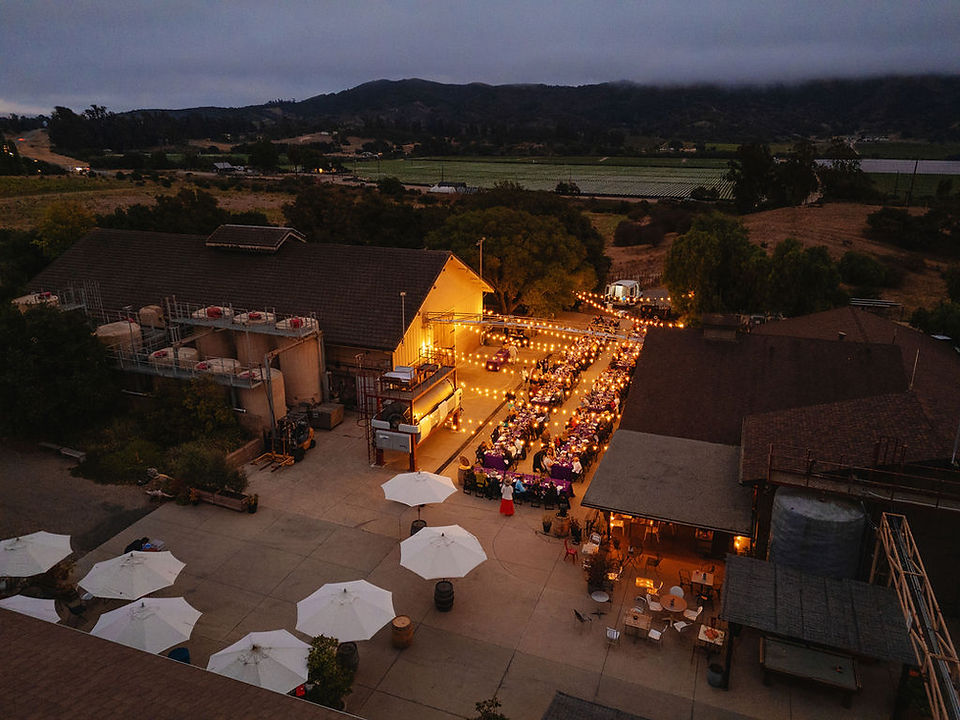 Overhead view of a Wine & Fire evening event illuminated by string lights in the Sta. Rita Hills.