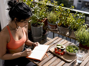 Woman planning time-restricted eating schedule at kitchen table.