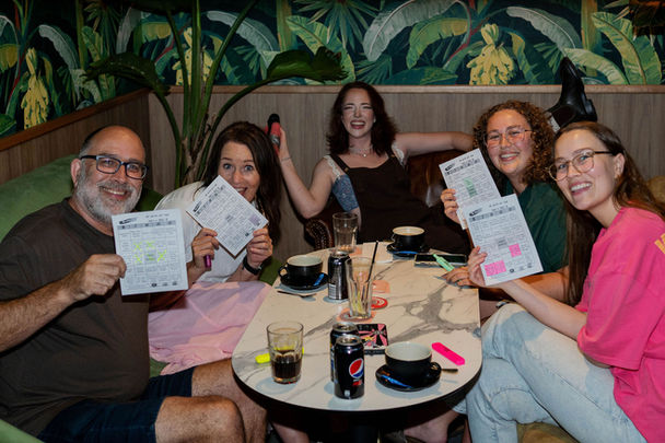 Friends holding scorecards while playing trivia for venues.