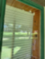 Horizontal window blinds pulled down in a green frame