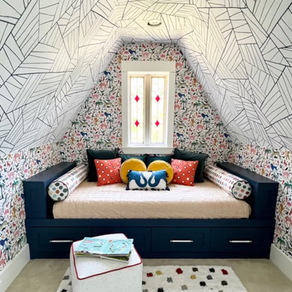 A daybed with storage, colorful wallpaper and pillows with square ottomans.