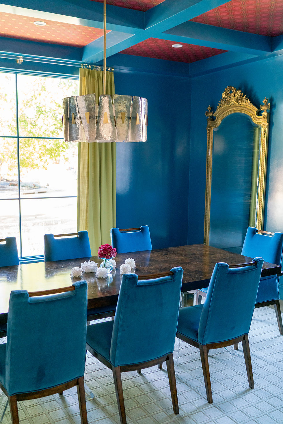 Dining room painted in a bold teal with a red patterned wallpaper on the ceiling.