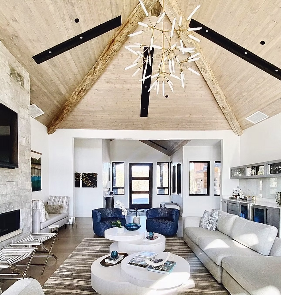 Living room in Colorado mountain home with high ceilings, statement chandelier, open floor plan, stone fireplace, ivory sectional, and original art.