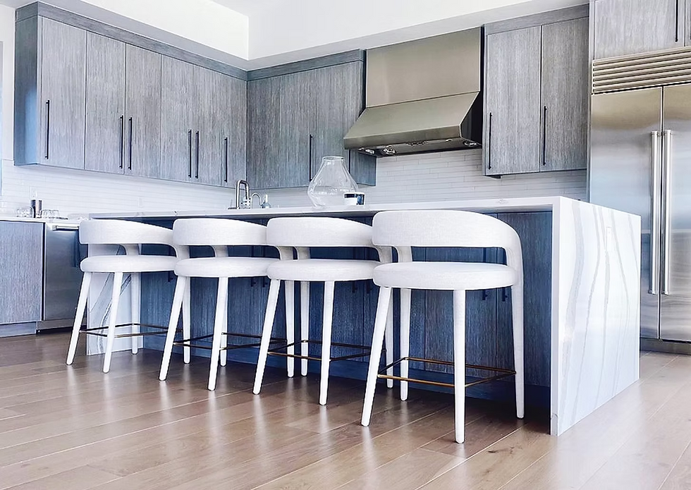 Kitchen with grey wood cabinetry, waterfall island and modern ivory upholstered counter stools.