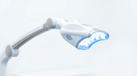 Profesyonel diş beyazlatma işleminde kullanılan modern LED ışık cihazının yakın plan görünümü. Klinik ortamda, temiz beyaz arka planda, sadece cihazın yer aldığı steril ve minimal bir görüntü.