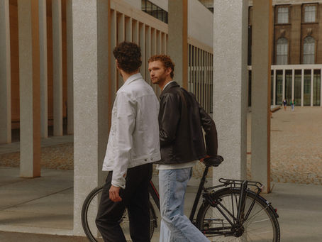 two men talking, one is holding a bicycle