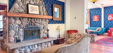 Great room with a river-rock fireplace and blue damask walls at The Delphine Lodge, Wilmer BC