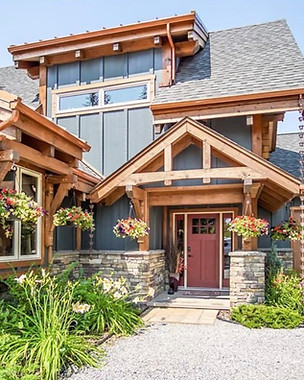 Timber-frame mountain home with stone accents, a red front door and hanging flower baskets