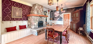 Dining room with a stone fireplace, window seat and harvest table at The Delphine Lodge, Wilmer BC