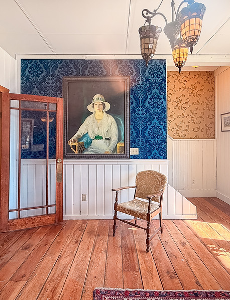 Sunlit room at The Delphine Lodge with a vintage portrait, blue damask wallpaper and original wood floors, Wilmer BC