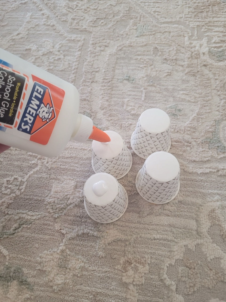 Four white Dixie cups, turned upside down and glue being placed on bottoms.