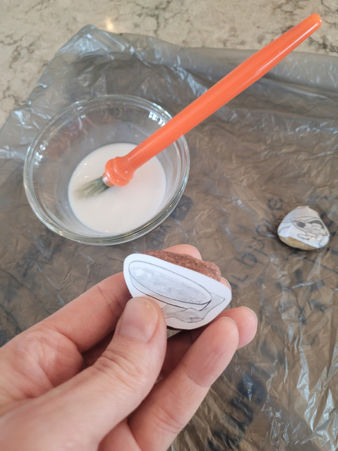 Gluing the pictures onto the flattest side of each rock.