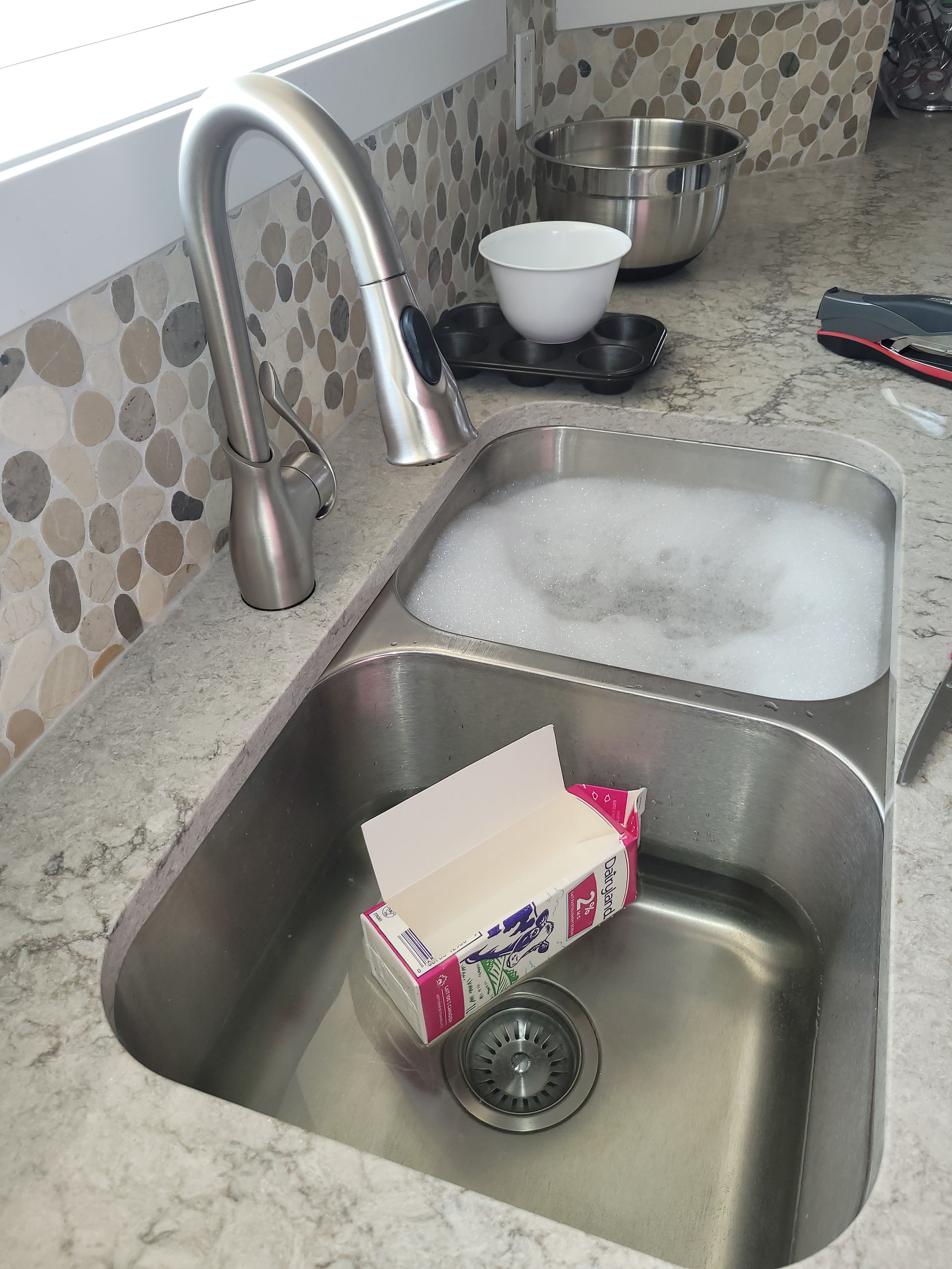 A cardboard milk carton with one side cut open, floating in a kitchen sink.Noah's Ark in the Sink | Free Bible Activities for Kids