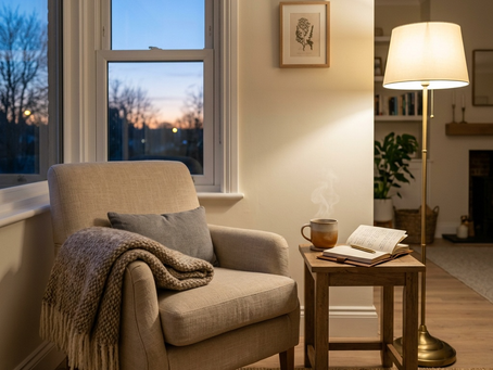 A softly lit living room corner at dusk, cozy armchair by a window, warm lamp light, soft neutral tones