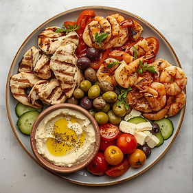 Mediterranean-mezze-plate-with-grilled-protein-fresh-vegetables-olives-and-hummus-or-baba-